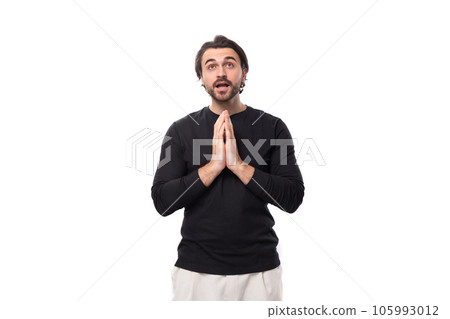 young brutal handsome brunet european man in a black sweater prays for good luck on an isolated 105993012
