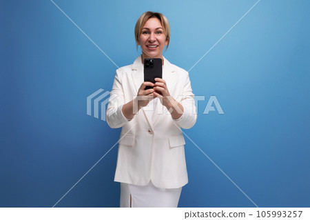 young European fair-haired business woman in a white jacket and dress solves work issues on the 105993257