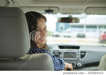 Young stylish woman driver sitting behind steering wheel of her car. Driving vehicle concept 105993415
