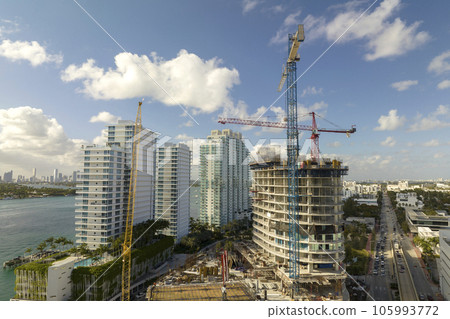 Tower lifting cranes at high residential apartment building construction site. Real estate development in Miami urban area Tower lifting cranes at high residential apartment building construction site. Real estate development in Miami urban area 105993772