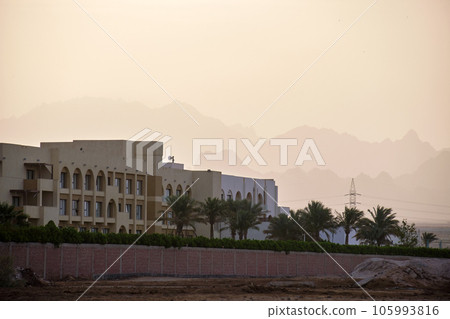 Sunset landscape with remote hotel complex against dark mountain peaks in egyptian desert 105993816