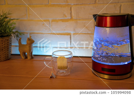 A glass electric kettle on a wooden table and a transparent mug  105994098