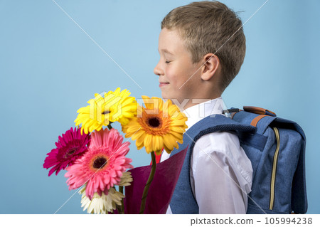first grader with a backpack holds a bouquet of flowers 105994238