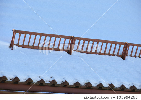 Snow guard for safety in winter on house roof top covered with ceramic shingles. Tiled covering of building Snow guard for safety in winter on house roof top covered with ceramic shingles. Tiled covering of building 105994265