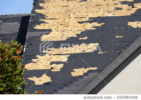 Ruined rooftop in need of repair. Wind damaged house roof with missing asphalt shingles after hurricane Ian in Florida Ruined rooftop in need of repair. Wind damaged house roof with missing asphalt shingles after hurricane Ian in Florida 105994306