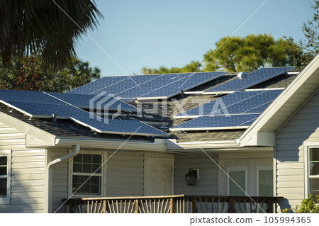 Residential house with rooftop covered with solar photovoltaic panels for producing of clean ecological electrical energy in suburban rural area. Concept of autonomous home 105994365