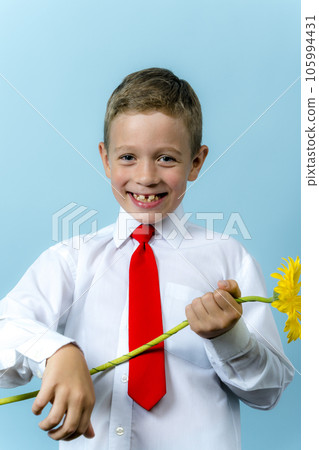 first grader in a white shirt with a backpack holds a bouquet of flowers first grader in a white shirt with a backpack holds a bouquet of flowers 105994431