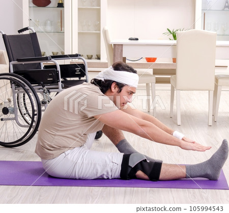 Injured young man doing exercises at home Injured young man doing exercises at home 105994543