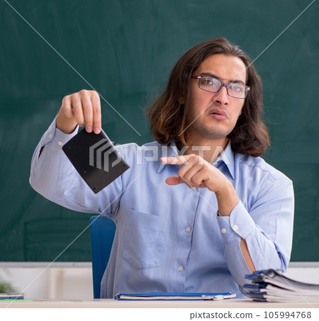 Young male teacher in front of green board 105994768