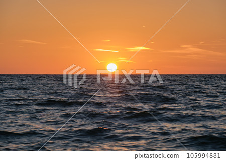 Ocean sunset. Big white sun on dramatic bright sky background, soft evening cloud over sea dark water 105994881