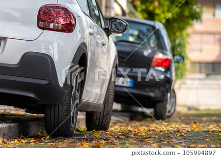 Modern cars parked on city street side in residential discrict. Shiny vehicles parked by the curb. Urban transportation infrastructure concept. 105994897