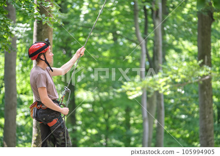 Man belays his partner climber with belaying device and rope. Climber's handsman holding equipment for rock mountaineering security. Man belays his partner climber with belaying device and rope. Climber's handsman holding equipment for rock mountaineering security. 105994905