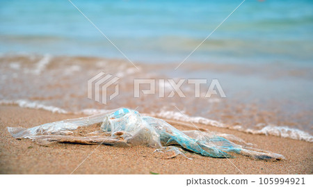 Left behind plastic bag garbage on sandy beach. Empty used dirty litter on sea shore. Environmental pollution. Ecological problem 105994921