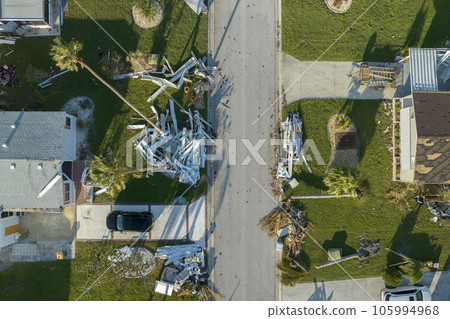 Heaps of debris rubbish on street side near severely damaged by hurricane Ian houses in Florida mobile home residential area. Consequences of natural disaster 105994968