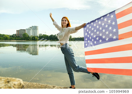 Happy young woman with United States national flag in her hand. Positive girl celebrating US independence day. International day of democracy concept. 105994969