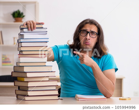 Young male student and a lot of books in the class 105994996