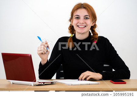 Happy young office worker woman sitting behind working desk with laptop computer, cell phone and notebook. Happy young office worker woman sitting behind working desk with laptop computer, cell phone and notebook. 105995191