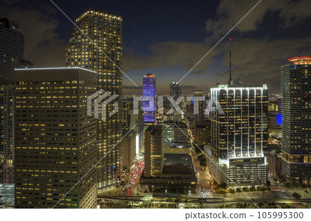 Downtown district of of Miami Brickell in Florida, USA. Brightly illuminated high skyscraper buildings and street with cars and Metrorail traffic in modern american midtown Downtown district of of Miami Brickell in Florida, USA. Brightly illuminated high skyscraper buildings and street with cars and Metrorail traffic in modern american midtown 105995300