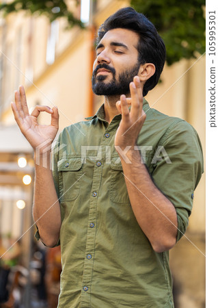 Portrait of indian man praying with closed eyes to God asking for blessing help forgiveness outdoors 105995301