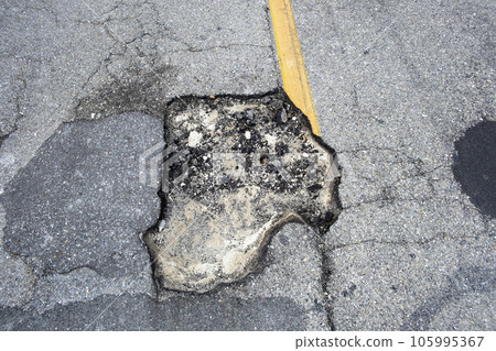 Dangerous pothole on american road surface. Ruined driveway in urgent need of repair Dangerous pothole on american road surface. Ruined driveway in urgent need of repair 105995367