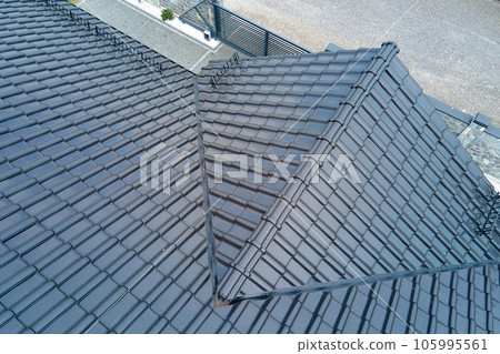 Closeup of house roof top covered with shiny ceramic shingles. Closeup of house roof top covered with shiny ceramic shingles. 105995561