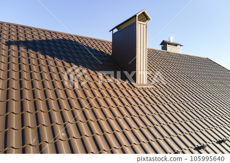 Chimney on house roof top covered with metallic shingles under construction. Tiled covering of building. Real estate development 105995640