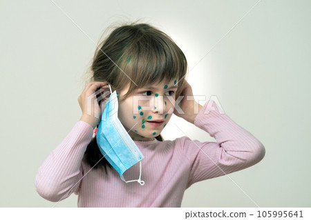Child girl wearing blue protective medical mask ill with chickenpox, measles or rubella virus with rashes on body. Children protection during epidemic of coronovirus. Covid-19 contagion concept. 105995641