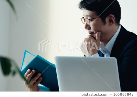Businessman worried about looking at documents 105995942