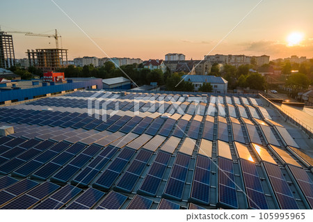 Blue photovoltaic solar panels mounted on building roof for producing clean ecological electricity at sunset. Production of renewable energy concept 105995965