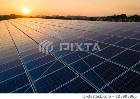 Blue photovoltaic solar panels mounted on building roof for producing clean ecological electricity at sunset. Production of renewable energy concept. Blue photovoltaic solar panels mounted on building roof for producing clean ecological electricity at sunset. Production of renewable energy concept. 105995966