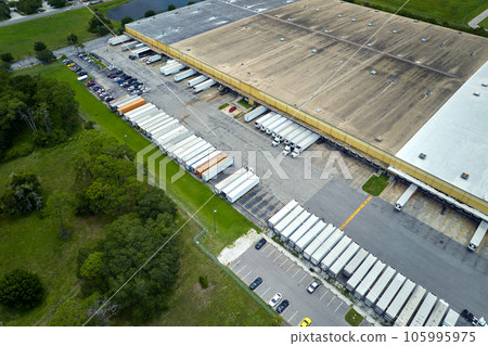 Big corporate shipment center with many cargo semi trucks unloading and uploading retail products for further retail shipment. Global market concept Big corporate shipment center with many cargo semi trucks unloading and uploading retail products for further retail shipment. Global market concept 105995975