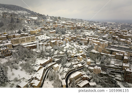 Aerial winter landscape of dense historic center of Thiers town in Puy-de-Dome department, Auvergne-Rhone-Alpes region in France. Rooftops of old buildings and narrow streets at snowfall 105996135