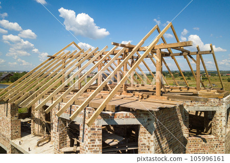 Aerial view of unfinished house with wooden roof frame structure under construction. 105996161