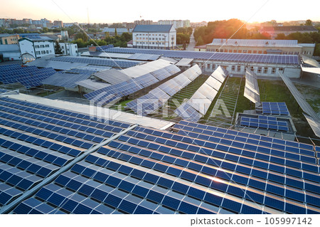 Aerial view of solar power plant with blue photovoltaic panels mounted on industrial building roof for producing green ecological electricity. Production of sustainable energy concept 105997142