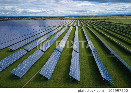 Aerial view of large sustainable electrical power plant with rows of solar photovoltaic panels for producing clean electric energy. Concept of renewable electricity with zero emission Aerial view of large sustainable electrical power plant with rows of solar photovoltaic panels for producing clean electric energy. Concept of renewable electricity with zero emission 105997290