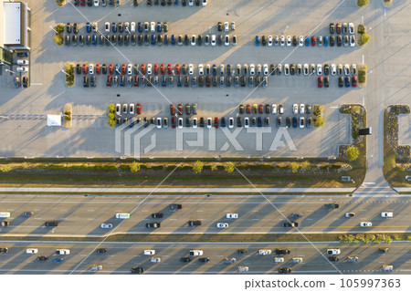 Aerial view of dealership parking lot with many brand new cars for sale near wide american highway. Development of US automotive industry concept 105997363
