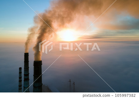 Aerial view of coal power plant high pipes with black smoke moving up polluting atmosphere at sunset. 105997382