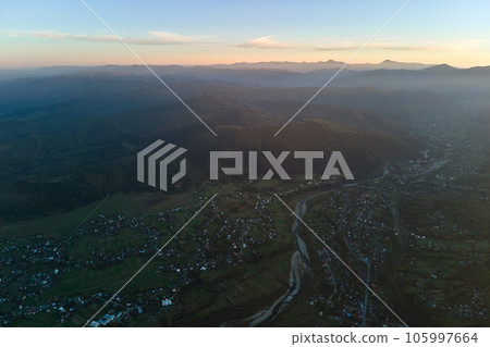 Aerial view from high altitude of residential houses in mountain village at sunset Aerial view from high altitude of residential houses in mountain village at sunset 105997664