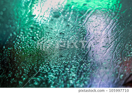 Abstract colorful background of glass surface with water drops and blurred city lights. 105997710