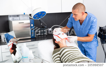 Woman receiving LED facial mask light therapy Woman receiving LED facial mask light therapy 105998507