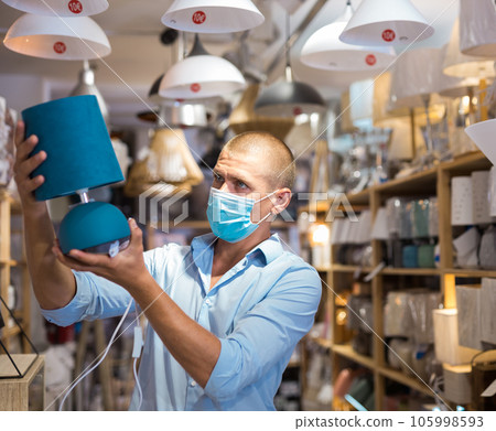 Man in mask buying lamp in furniture store 105998593