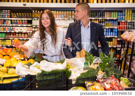 Happy young couple with a grocery cart in the supermarket shooses tangerines 105998638