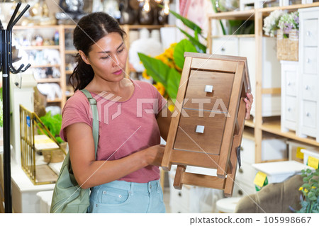 Asian female choosing wooden commode in store Asian female choosing wooden commode in store 105998667