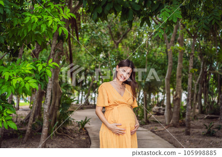 A serene and radiant pregnant woman after 40, surrounded by nature's beauty in the park, cherishing the journey of motherhood with a glowing smile A serene and radiant pregnant woman after 40, surrounded by nature's beauty in the park, cherishing the journey of motherhood with a glowing smile 105998885