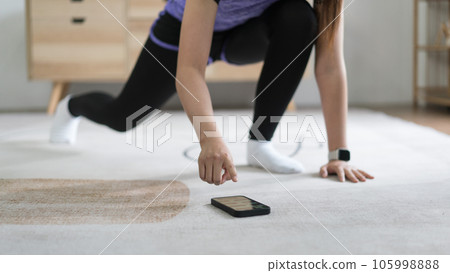 Young asian woman checking workout time on smartphone while doing exercise with healthy lifestyle Young asian woman checking workout time on smartphone while doing exercise with healthy lifestyle 105998888