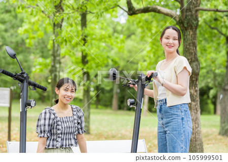 A young woman who meets on an electric kickboard and has a fun conversation | Electric kickboard image A young woman who meets on an electric kickboard and has a fun conversation | Electric kickboard image 105999501