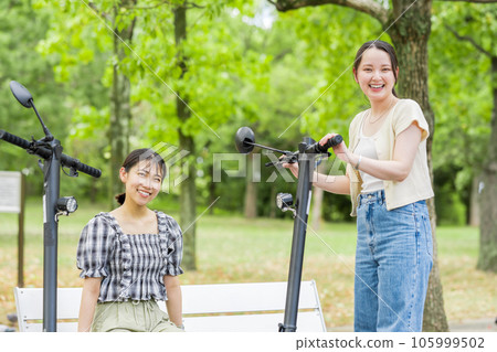 A young woman who meets on an electric kickboard and has a fun conversation | Electric kickboard image A young woman who meets on an electric kickboard and has a fun conversation | Electric kickboard image 105999502
