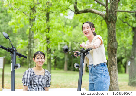 A young woman who meets on an electric kickboard and has a fun conversation | Electric kickboard image A young woman who meets on an electric kickboard and has a fun conversation | Electric kickboard image 105999504
