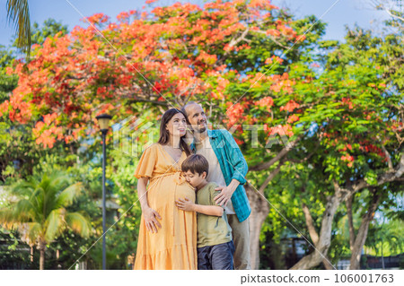 A loving family enjoying a leisurely walk in the park - a radiant pregnant woman after 40, embraced by her husband, and accompanied by their adult teenage son, savoring precious moments together A loving family enjoying a leisurely walk in the park - a radiant pregnant woman after 40, embraced by her husband, and accompanied by their adult teenage son, savoring precious moments together 106001763