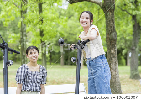 A young woman who meets on an electric kickboard and has a fun conversation | Electric kickboard image A young woman who meets on an electric kickboard and has a fun conversation | Electric kickboard image 106002007